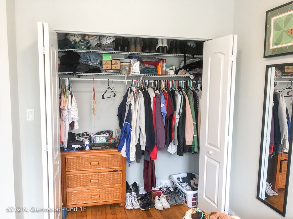 a closet with a rack of clothes and a dresser in it
