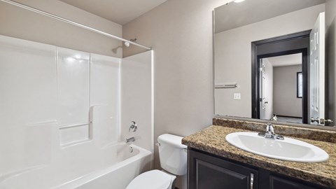 A bathroom with a white tub, sink, and toilet.