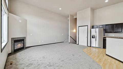A spacious living room with a fireplace and a staircase leading to the upper floor.