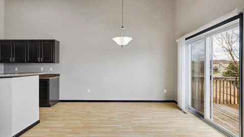 A kitchen with a white counter and black cabinets with a wooden floor and a hanging light.