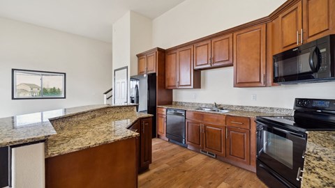 A kitchen with brown cabinets and black appliances.