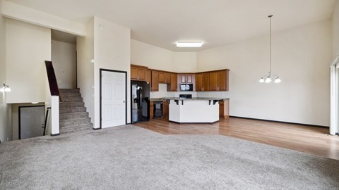 A spacious living room with a grey carpet and wooden flooring.
