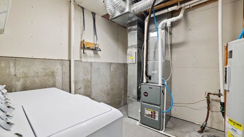 A white washing machine is in a laundry room with a dryer in the background.