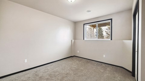 A room with a window showing trees outside.