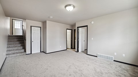 A spacious room with a staircase and a carpeted floor.