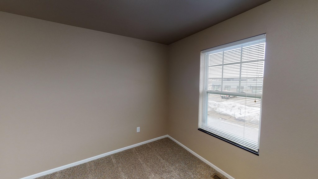 an empty bedroom with a large window and carpeting