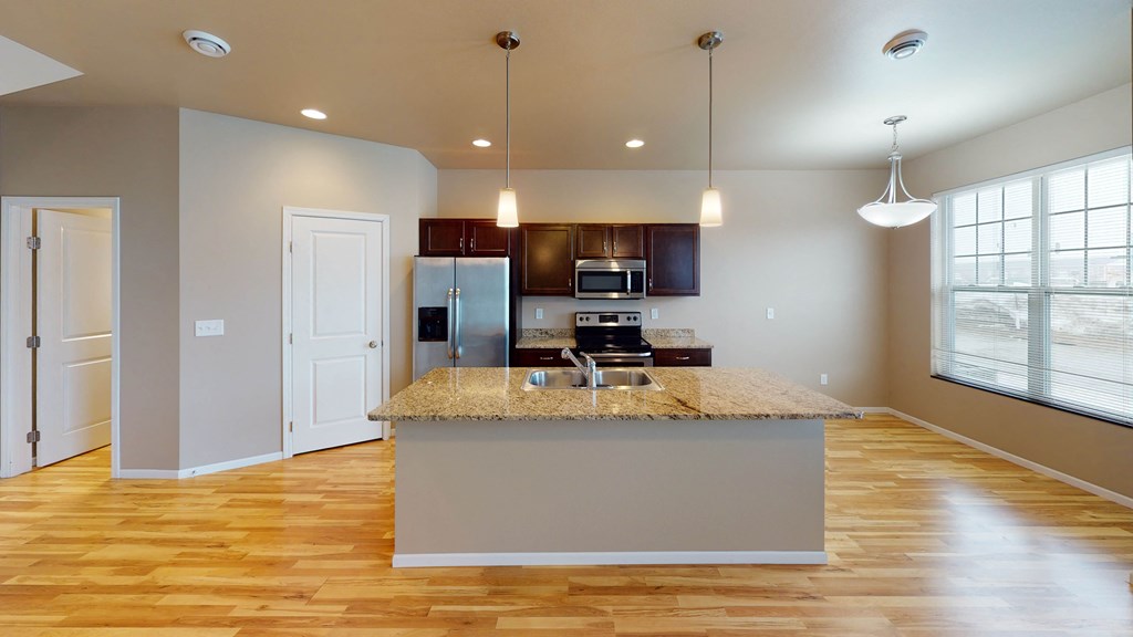 an open kitchen with a large island with a granite counter top