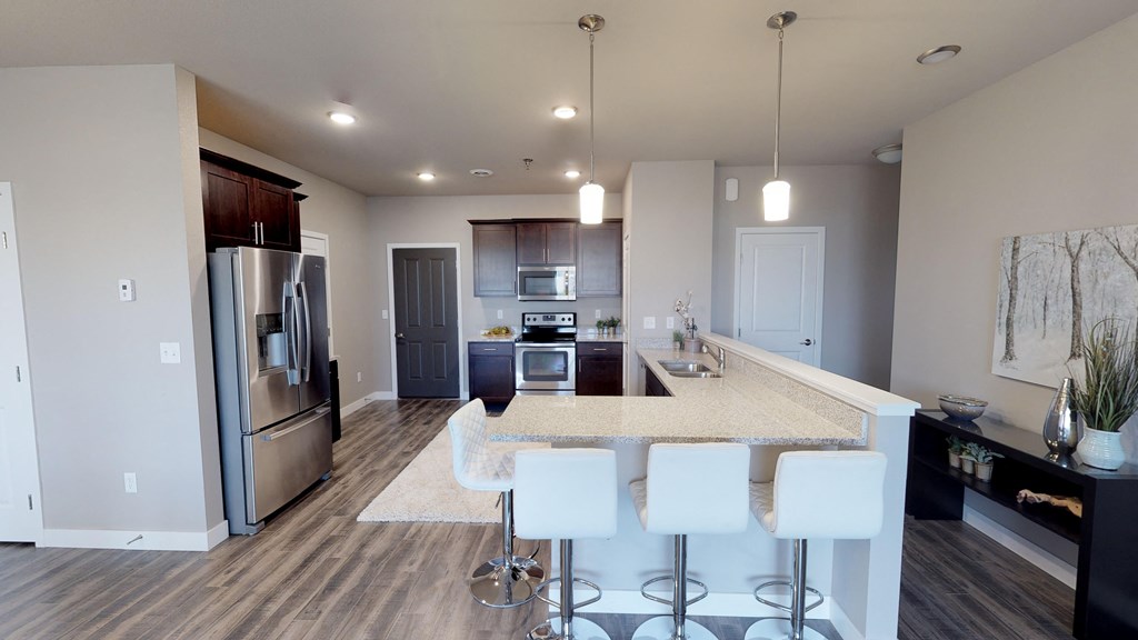 a kitchen with stainless steel appliances and an island with white chairs