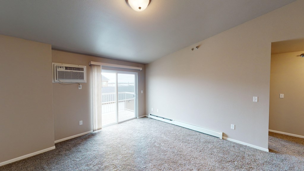 an empty living room with a door to a balcony
