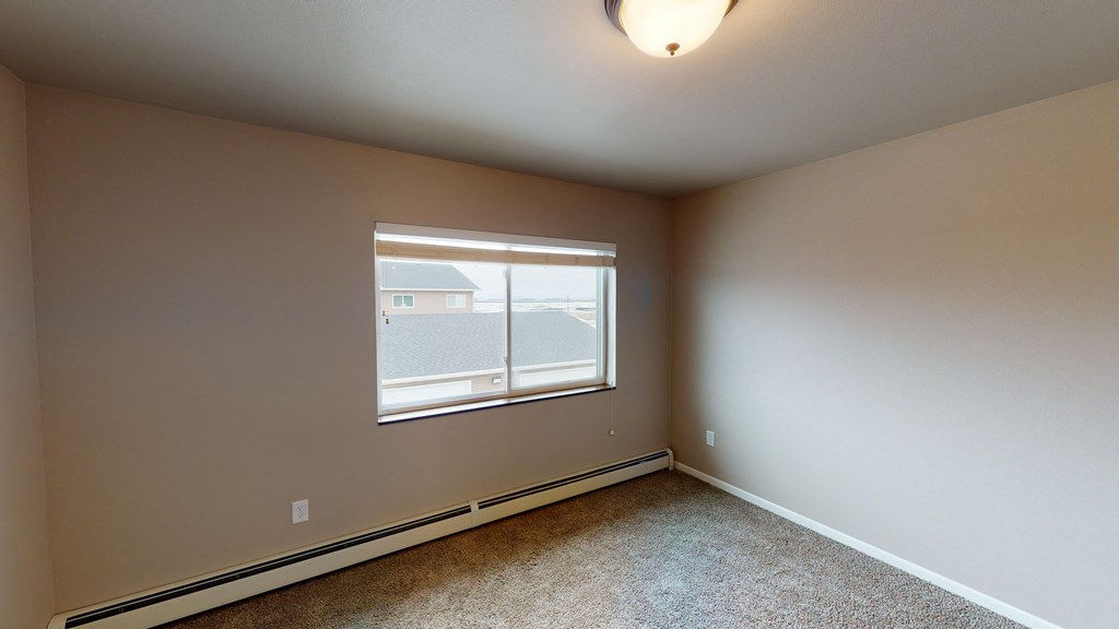 an empty bedroom with a large window and carpeting