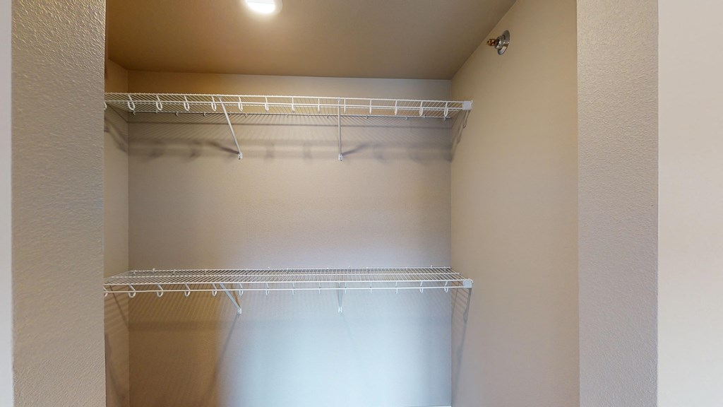 a walk in closet in an empty room with a ceiling light