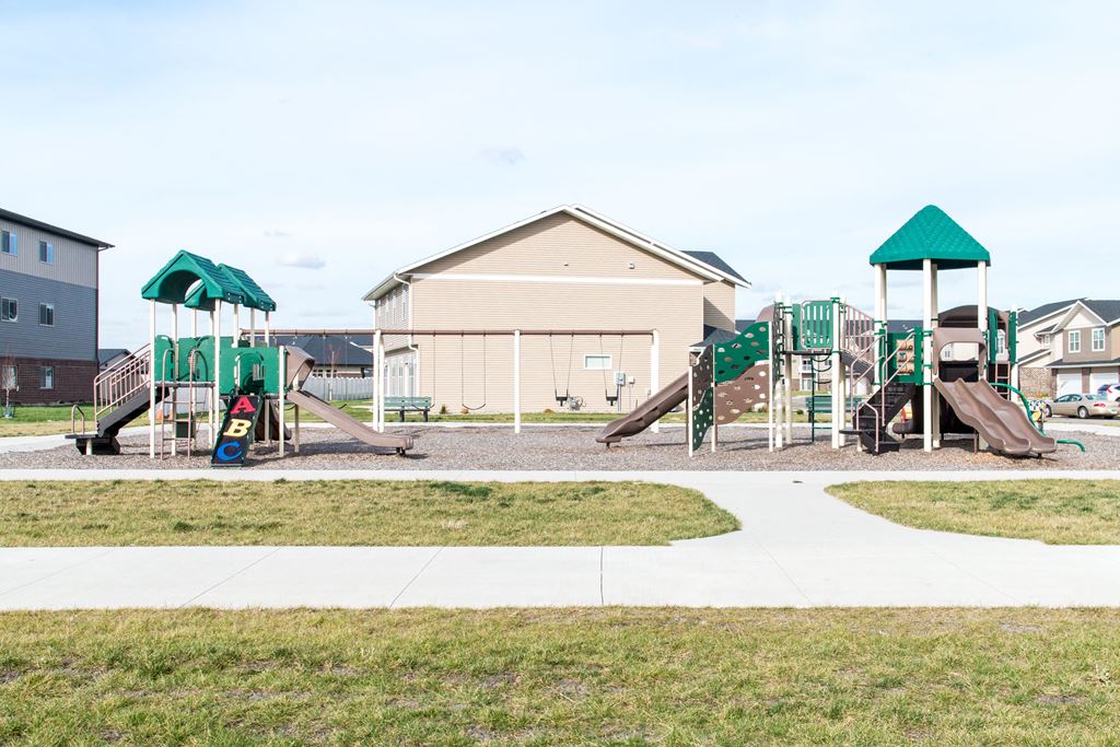 a playground with a swing set and slides in front of a house
