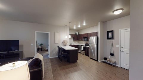 an open kitchen and living room with a dining room table and a refrigerator