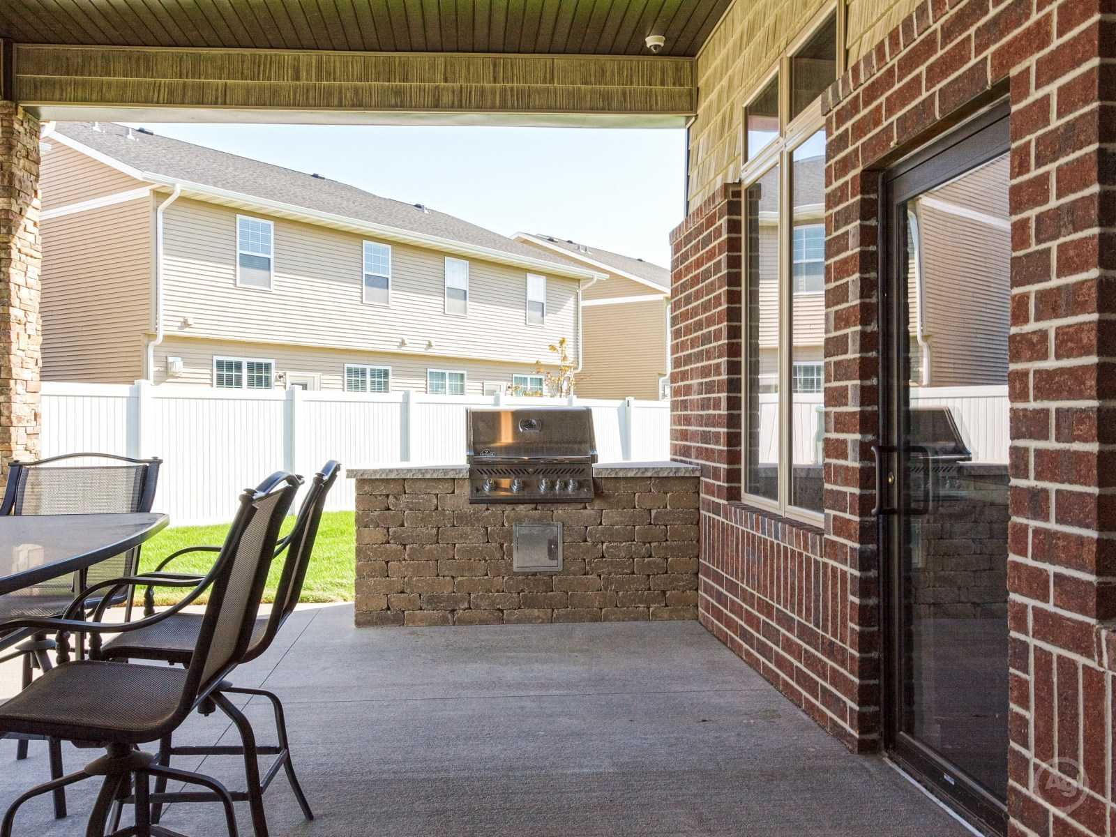 a patio with a grill and chairs on it