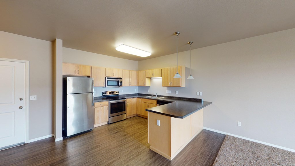 an empty kitchen with stainless steel appliances and wooden cabinets