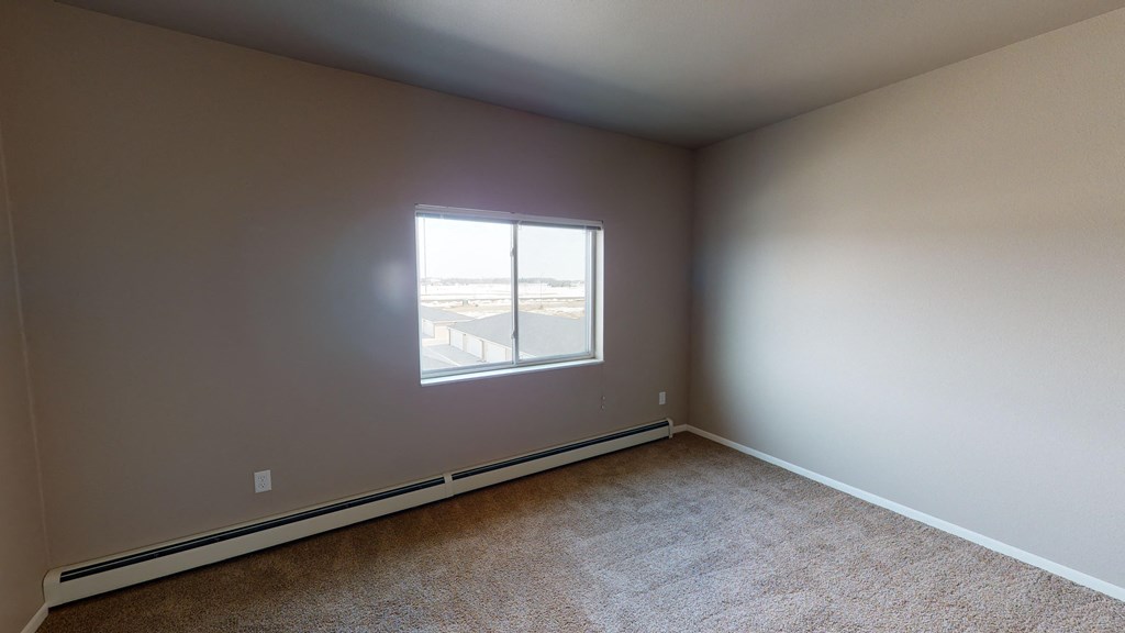 an empty room with a window and carpeting