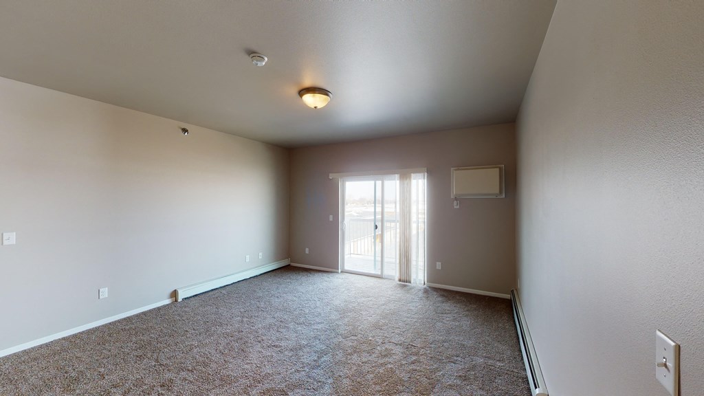 an empty living room with a door to a balcony