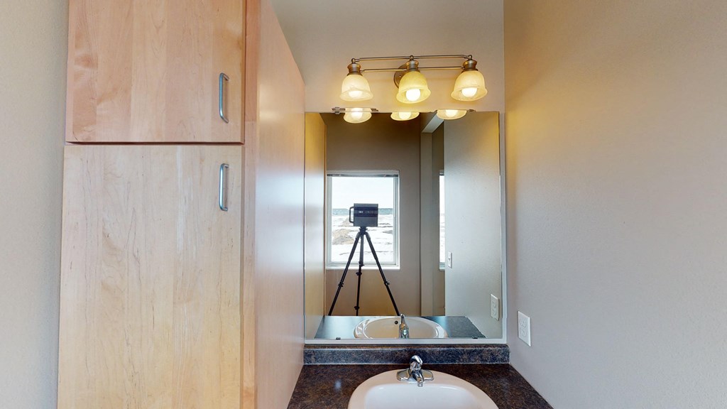 a bathroom with a sink and a mirror and a camera on a tripod
