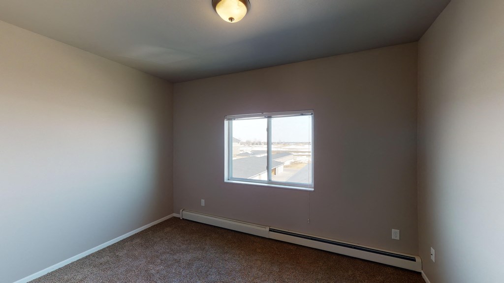 an empty living room with a window and carpet