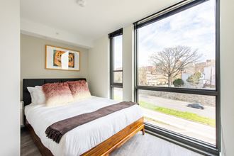 a bedroom with a large window and a bed