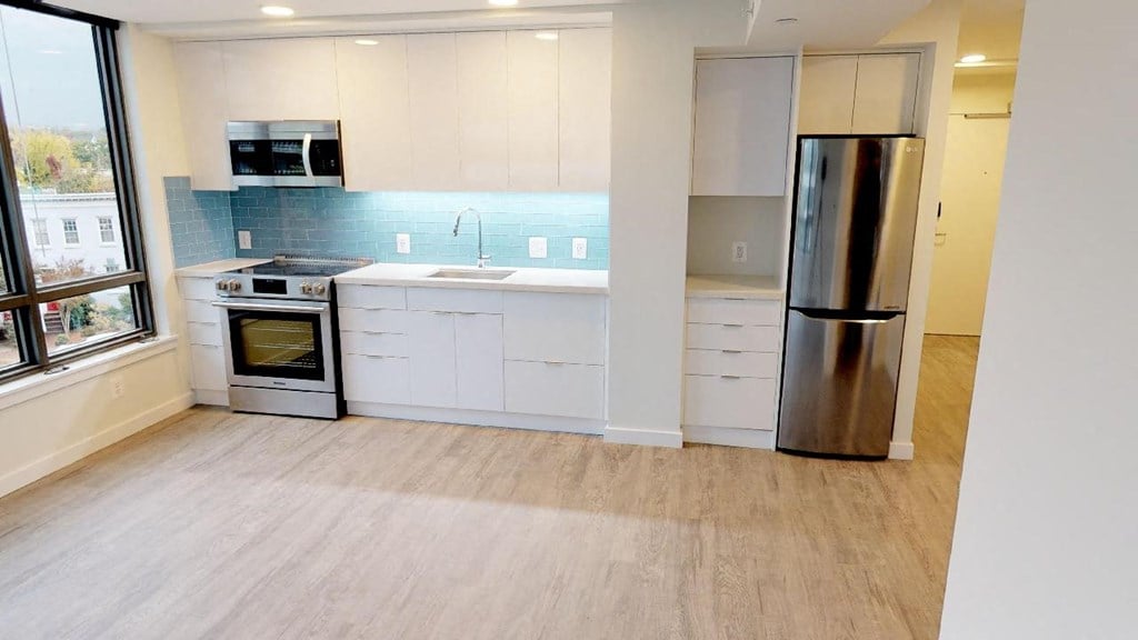 a kitchen with white cabinets and a stainless steel refrigerator