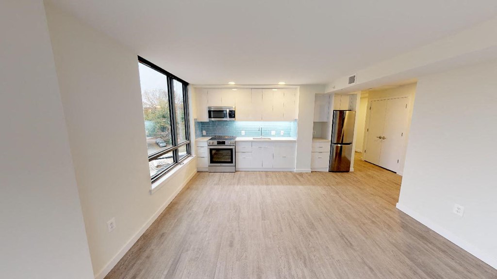 an empty living room and kitchen with a large window