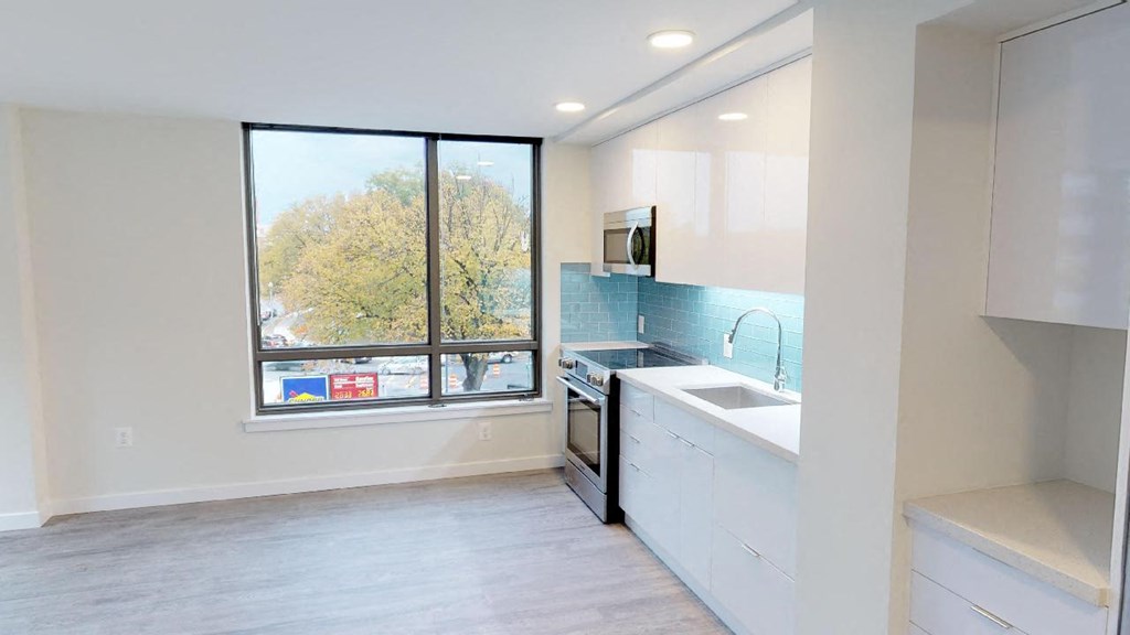 an empty kitchen with a large window and a sink