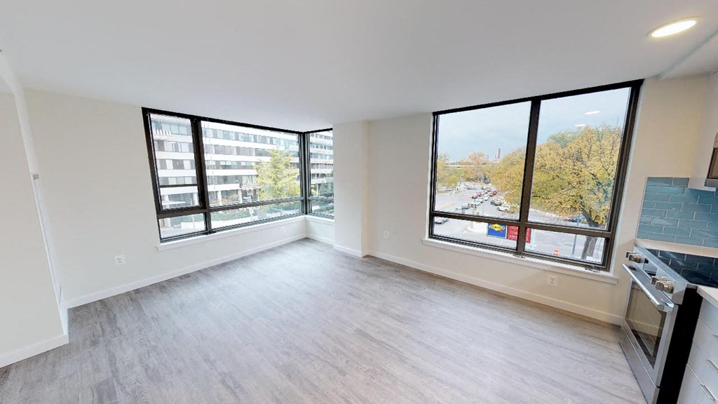 an empty living room with large windows and a stove