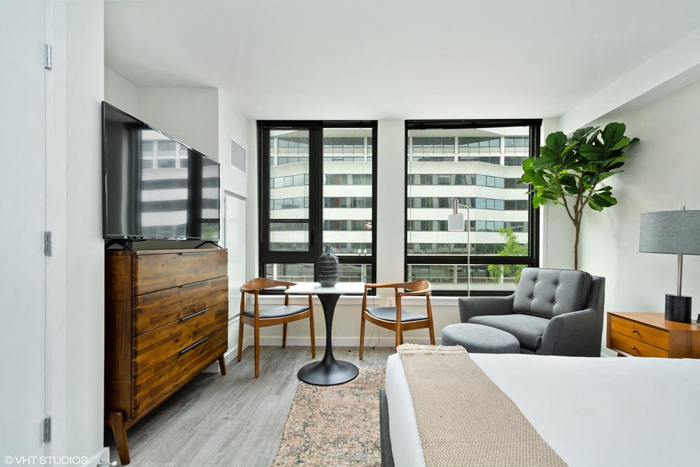 a bedroom with a bed and a desk and a balcony