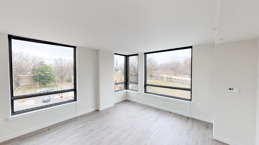 an empty living room with large windows and wood floors