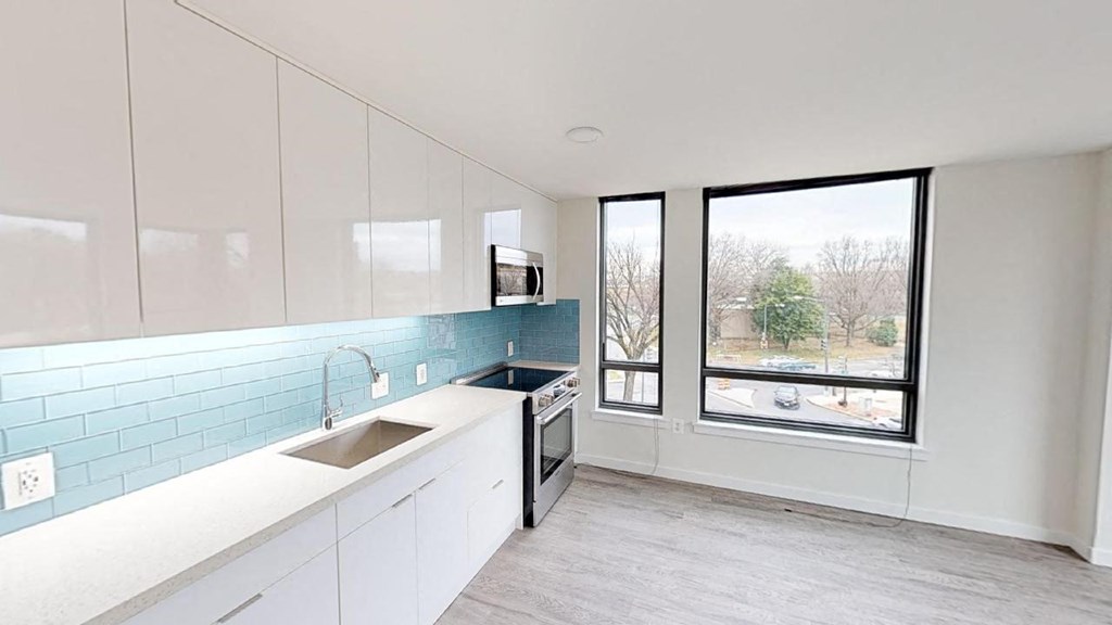 a white kitchen with a sink and a window