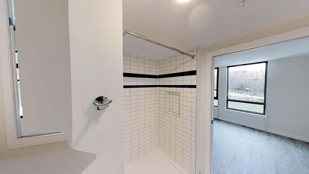 a white bathroom with a shower and a window