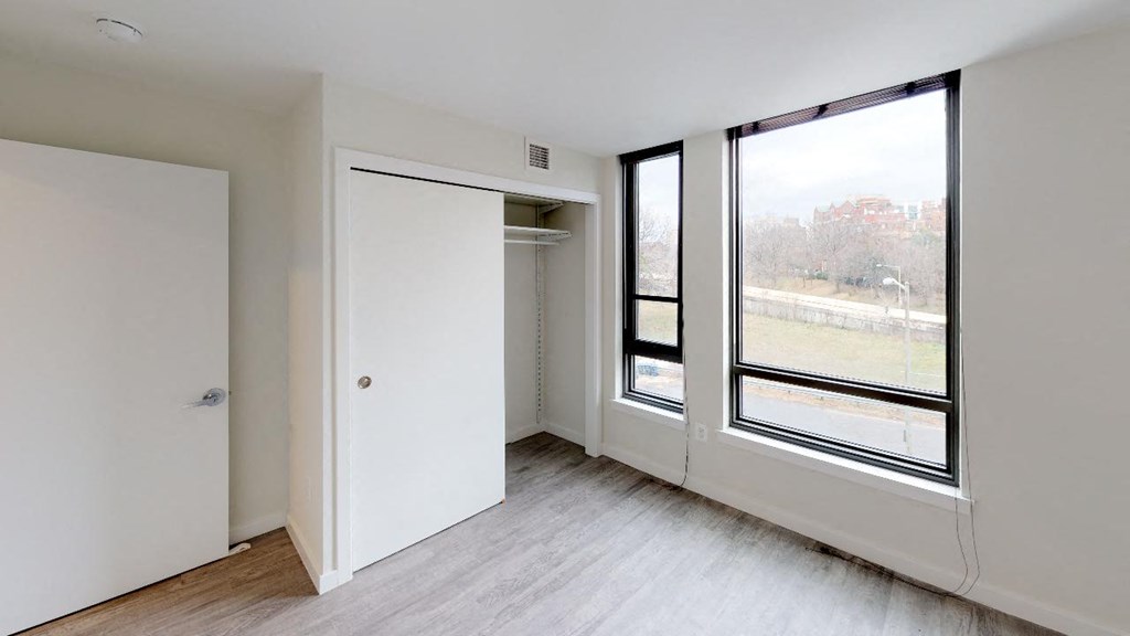 an empty living room with a large window and a closet