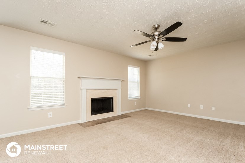 a living room with a fireplace and a ceiling fan