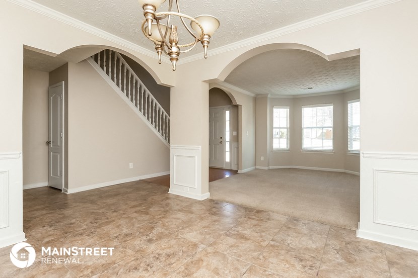 an empty living room with a staircase and a chandelier