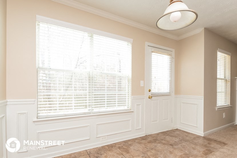 a dining room with white walls and a large window