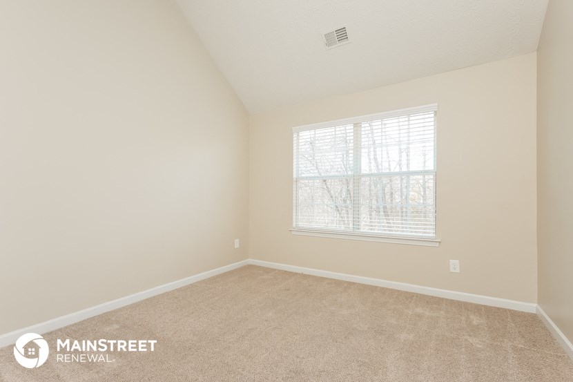 the upstairs bedroom with carpet and a window