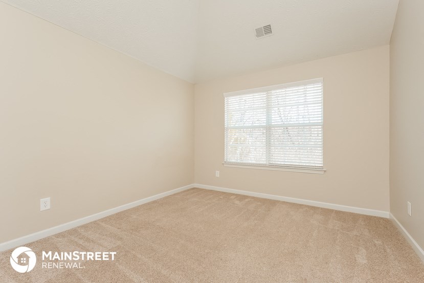 the upstairs bedroom with carpet and a large window