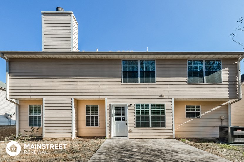 the front of a white house with a driveway and a blue sky