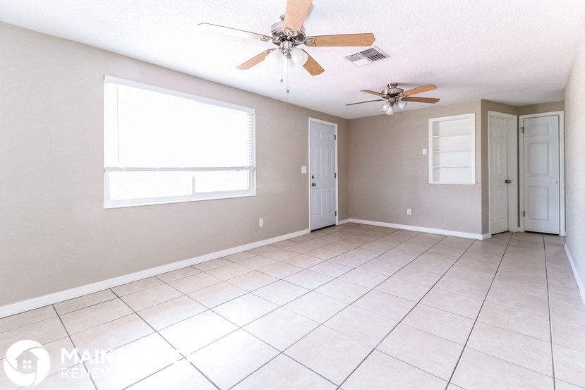 an empty living room with a ceiling fan and a window
