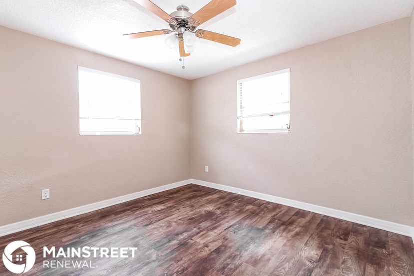 the living room of a home with a ceiling fan and wood floors