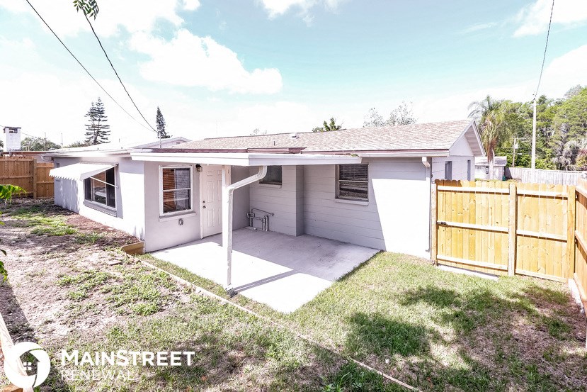 a small white house with a yard and a fence