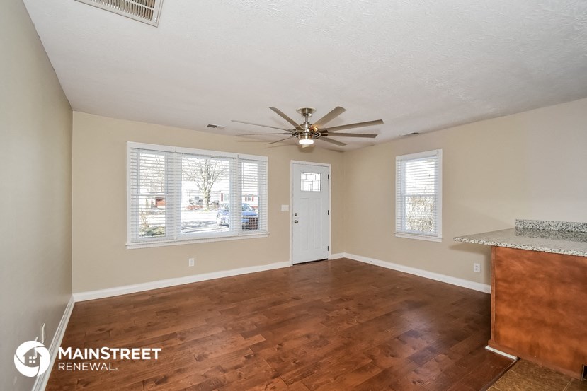 the living room and dining room with wood flooring and a ceiling fan