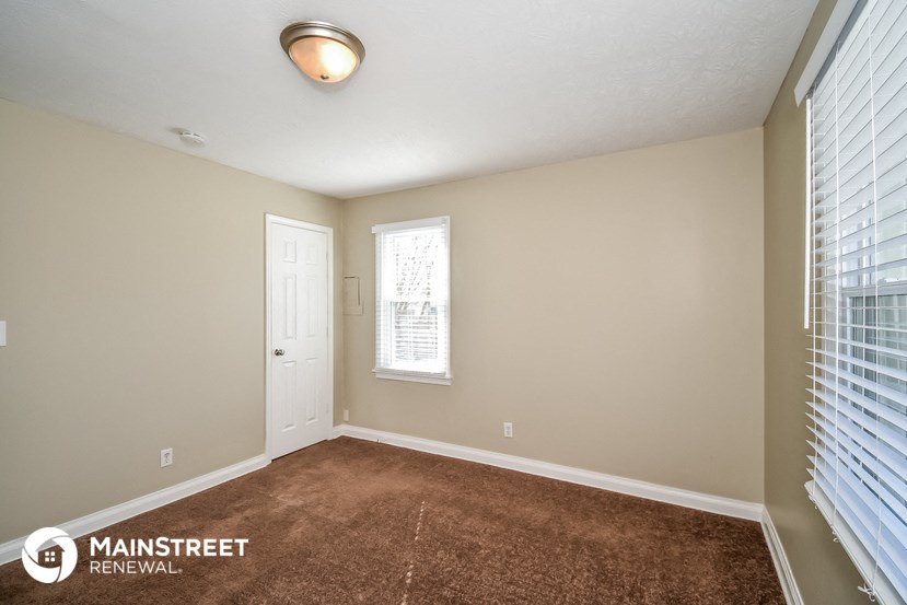 the spacious living room with carpeted flooring and a white door