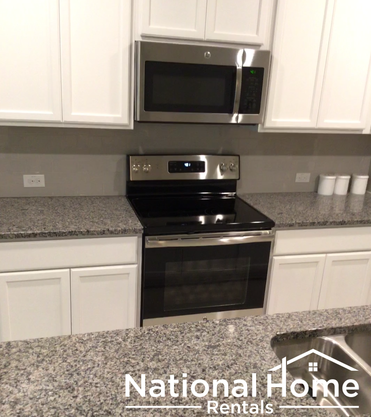 A kitchen with a granite countertop and a stove top oven.