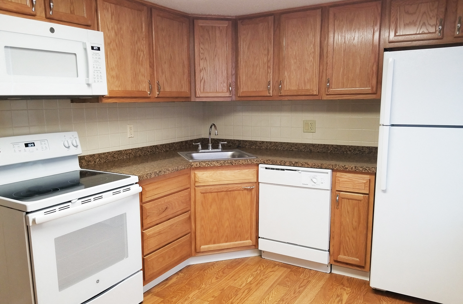 A kitchen with wooden cabinets and white appliances.