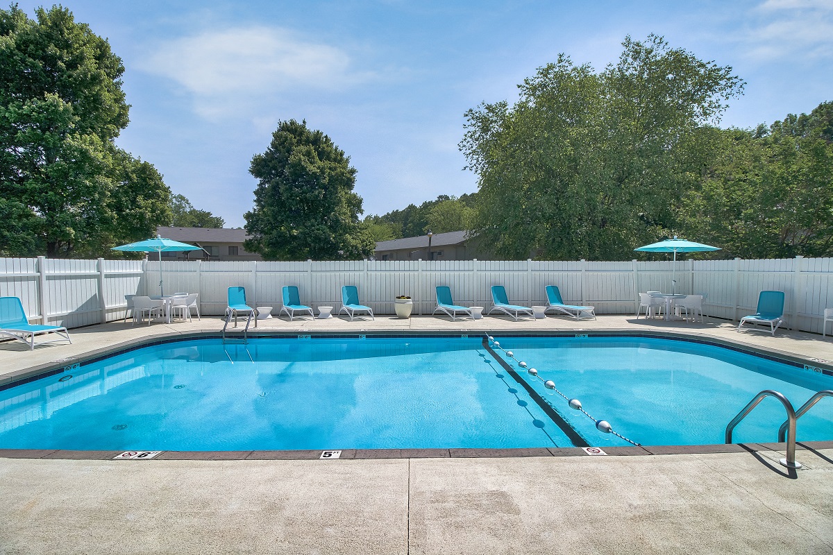 a swimming pool with blue chairs and umbrellas