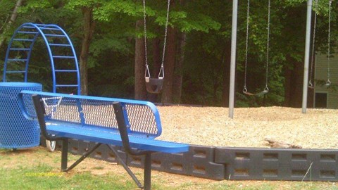 a blue park bench in front of a swing set