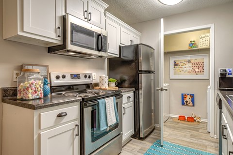 a kitchen with stainless steel appliances and white cabinets and a refrigerator