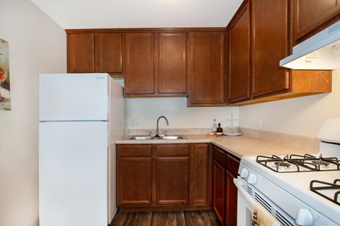 a kitchen with a white stove and refrigerator and wooden cabinets